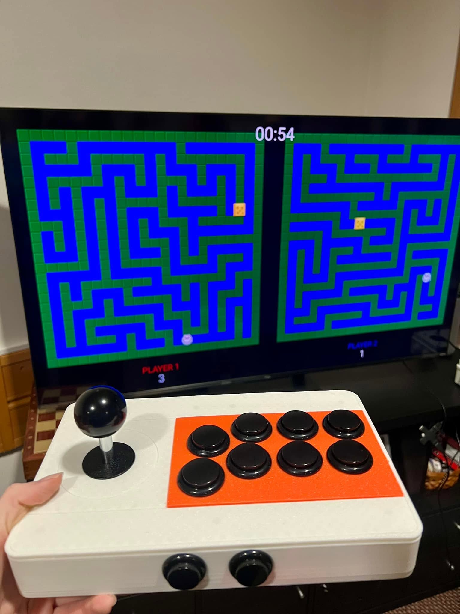 A close view of one handmade arcade controller and the two mazes on the TV.