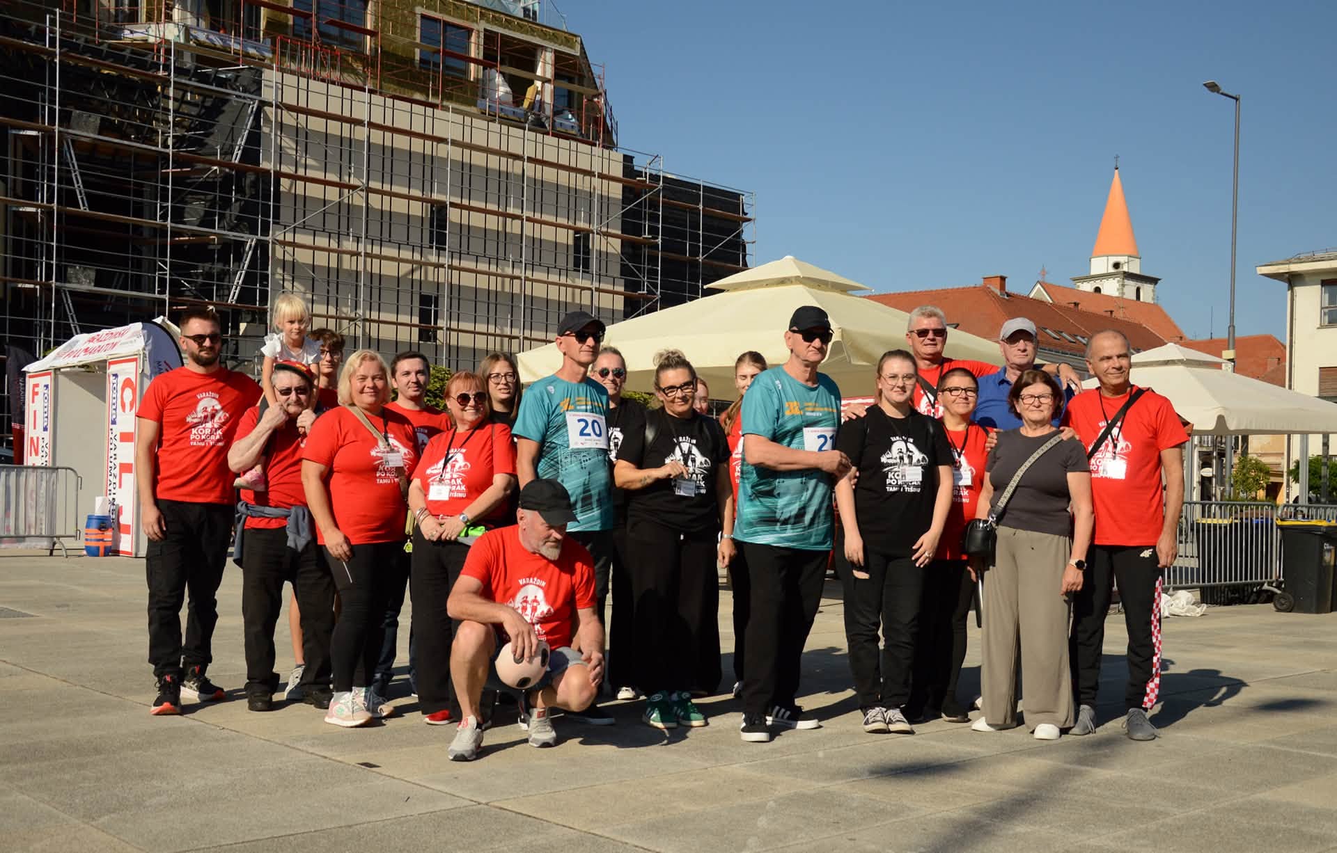 A group gathered at the race venue, including people in event shirts and race bibs.